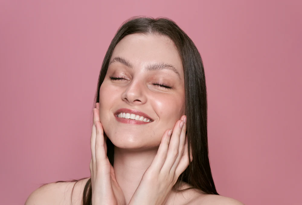 Mulher sentindo a pele facial após cuidados de skincare.