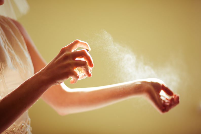 Mulher borrifando perfume no pulso.