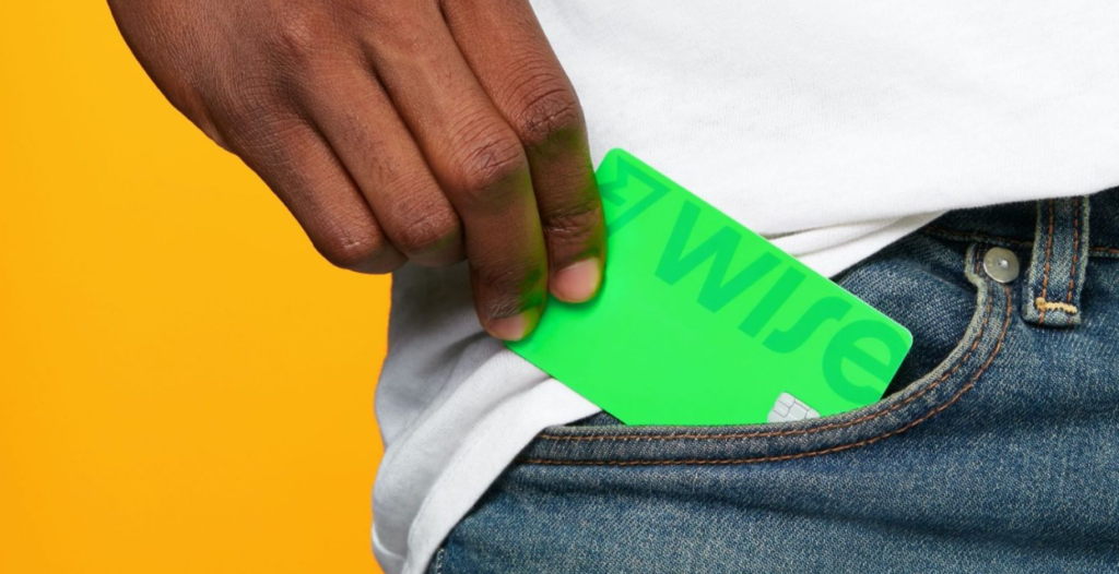 Mão de uma pessoa retirando um cartão verde do bolso da calça jeans.